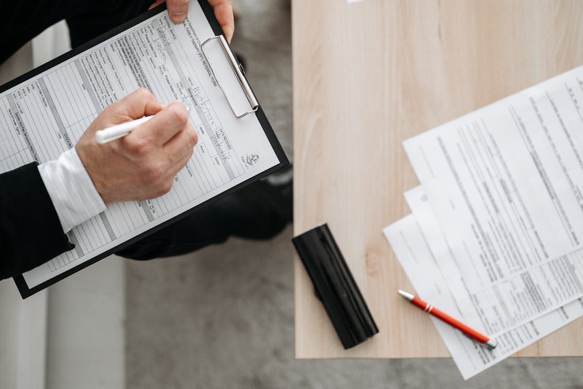 Person Holding a Pen and a Clipboard